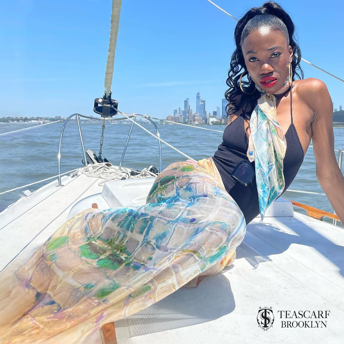 Model on a sailboat wearing the Calm Camomile silk chiffon art scarf.