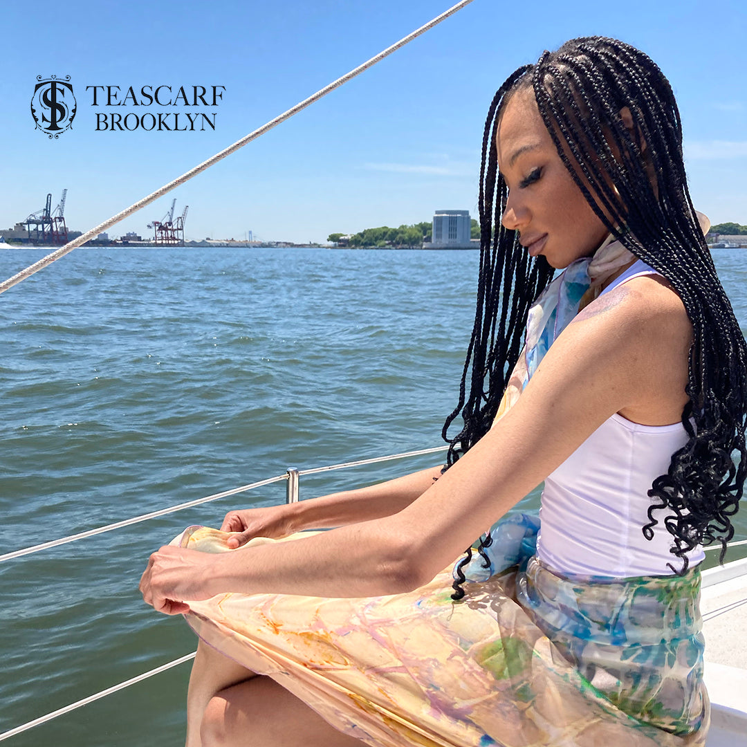 Girl on sailboat wearing a small Calm Camomile scarf tied around her neck and a large Calm Camomile scarf tied around her waist.
