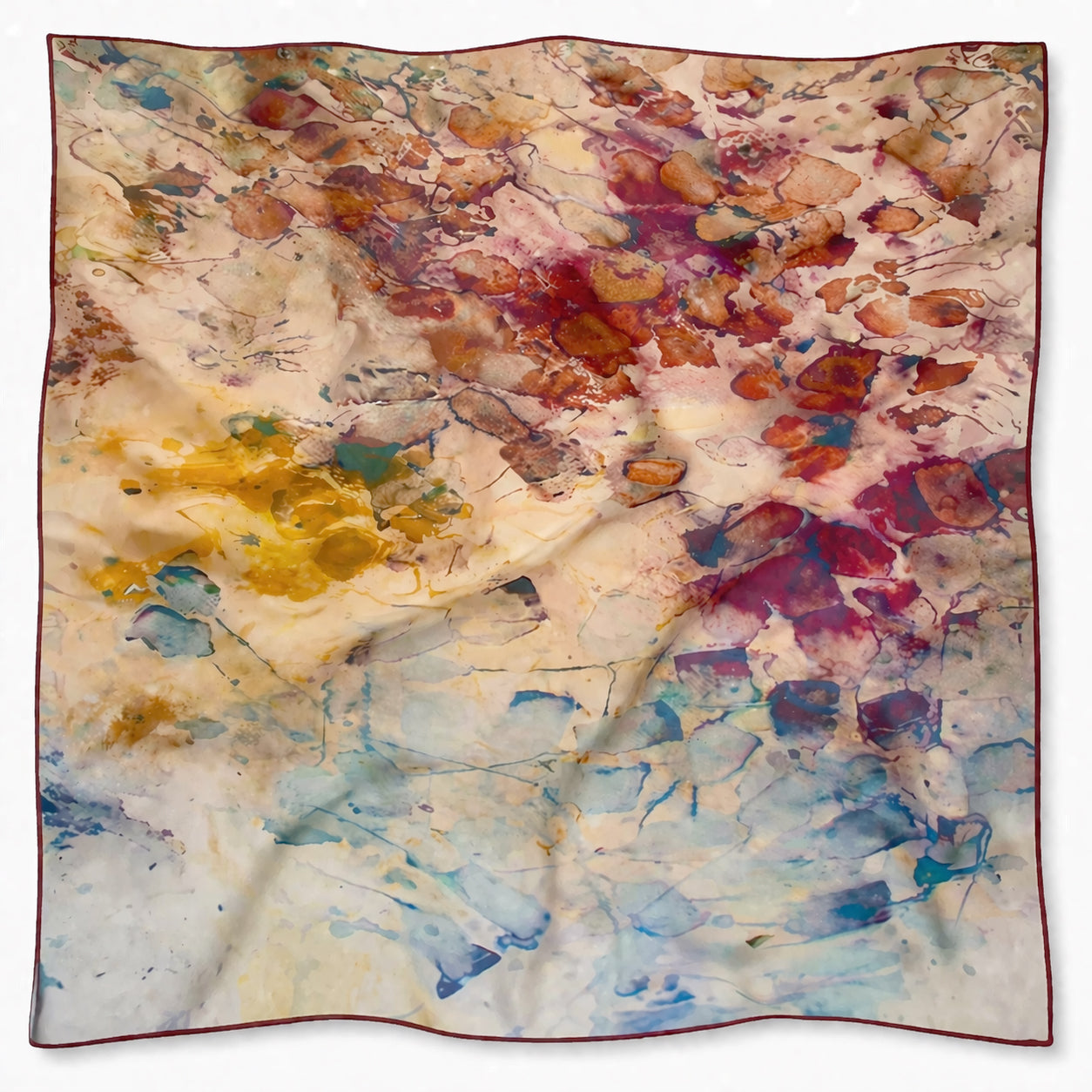24x24", tea-printed, tan, gold, brown, and red art scarf with burgundy hand a rolled edge on a white background.