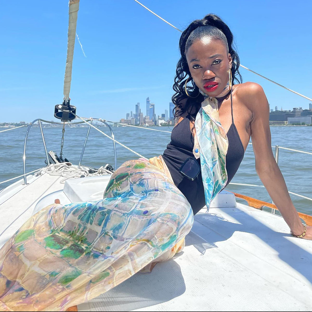 Model reclines, wearing Calm Camomile Tea-Printed Silk Chiffon Scarf in small 26x26" and oversized 52x52" sizes, crafted from 100% silk. Teascarf Brooklyn.