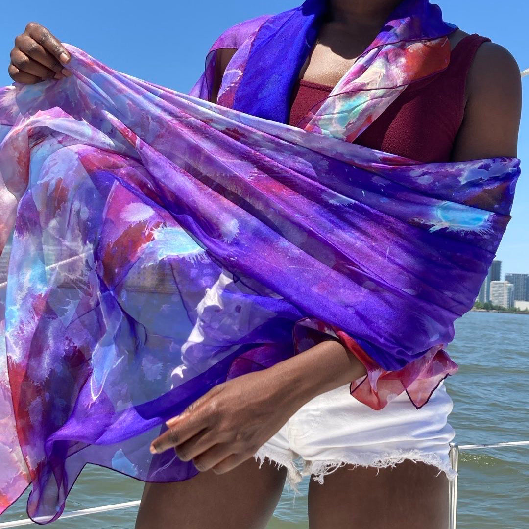 Model wraps oversized silk chiffon Purple Rain scarf around her body and small scarf drapes over her neck.