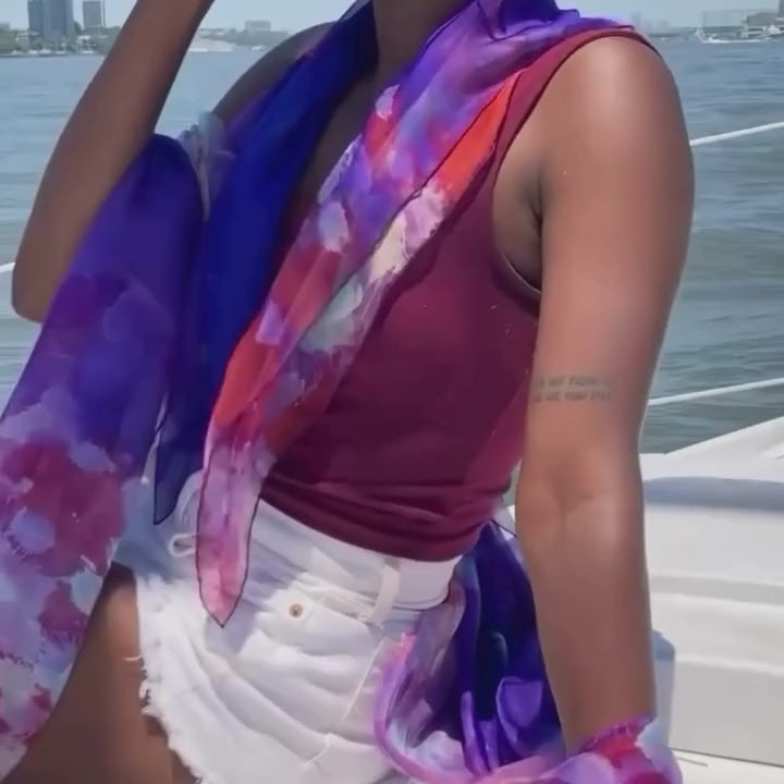 Model wearing small and oversized silk chiffon scarves while sitting on boat. Video.