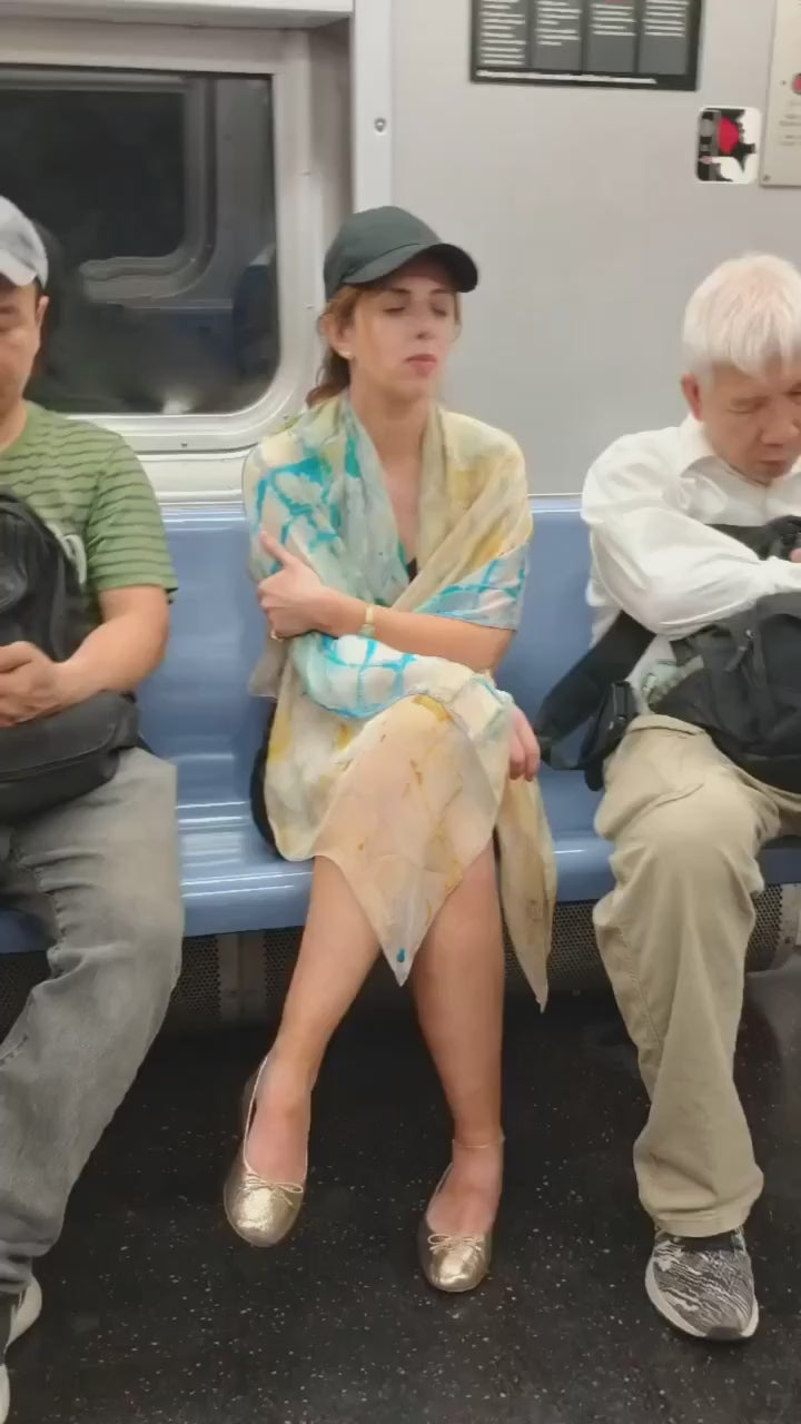 Woman stays comfortable on the chilly subway with a Calm Camomile Silk Chiffon Scarf.