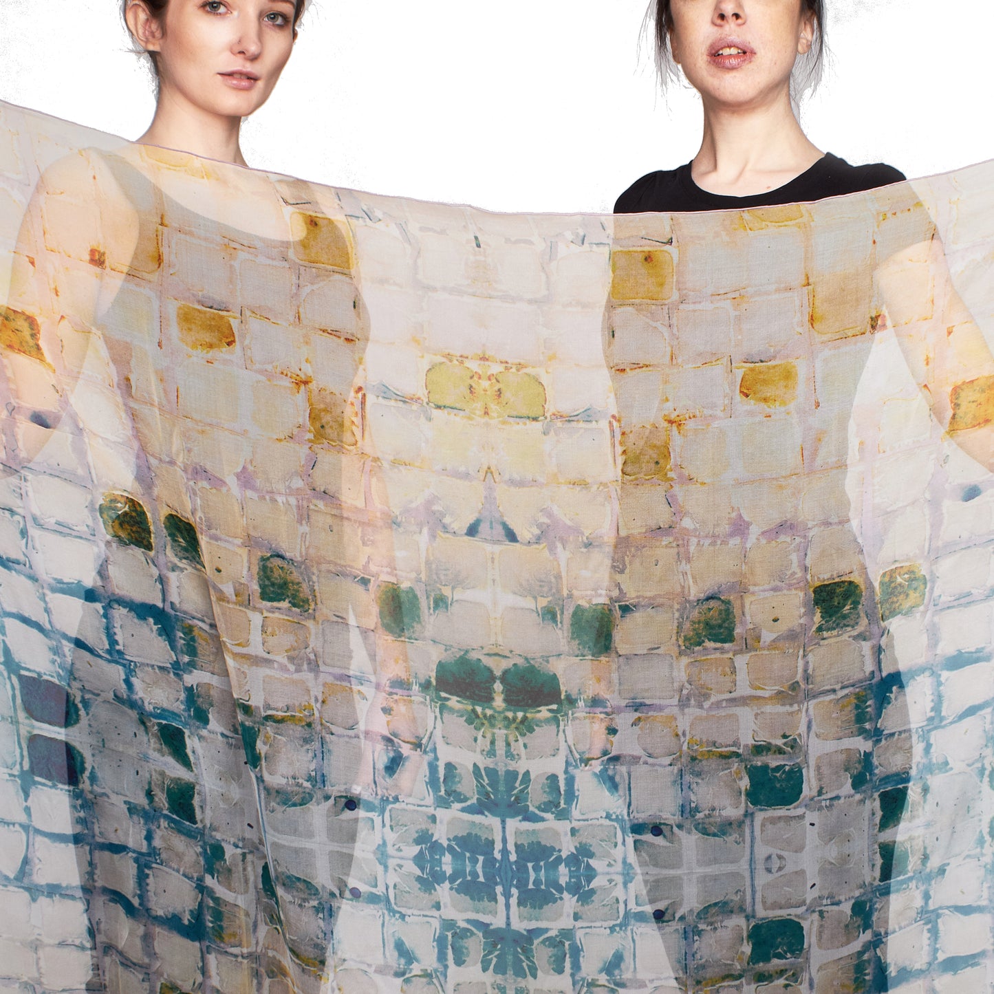 Two models stand behind a sheer silk chiffon Camomile Scarf from Teascarf Brooklyn.